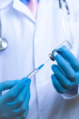 Şırınga ve ampul kullanarak doktor kolunu kapat. Beyaz bornoz giymiş, geçmişi bulanık. Tıbbi, aşılama ve aşılama kavramı