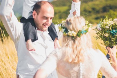 Sıcak ve güneşli yaz gününde buğday tarlasında birlikte yürüyen çocuklu mutlu bir aile. Yumuşak odaklama.