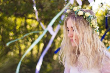 Güzel sarışın gelin portresi Kafasında çelenkle Yazın açık havada beyaz gelinlik, yumuşak bir odak