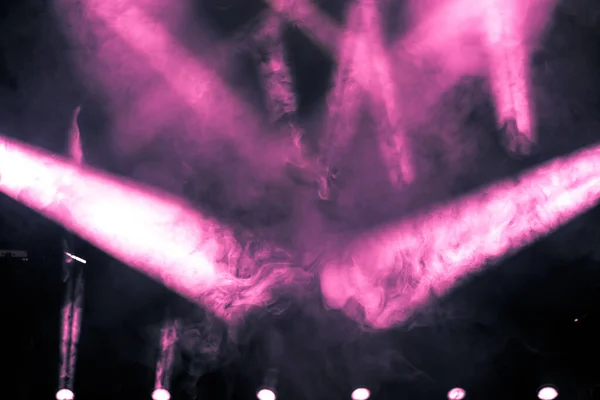 Pink ray of light with smoke and fog spotlights on the stage. Scene light equipment background