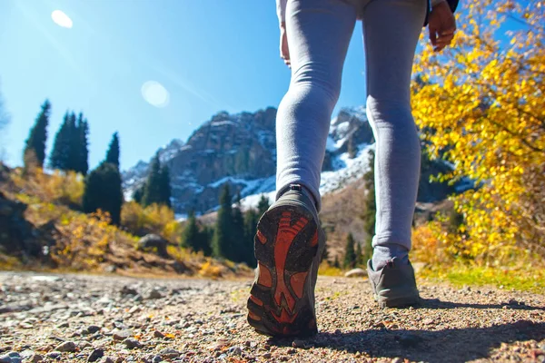 The legs of a sports man in shoes on a mountain road. Women sneakers.