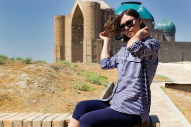 Beautiful young asian woman tourist in front of Mausoleum of Khoja Ahmed Yasawi. Central asia silk road tour clipart