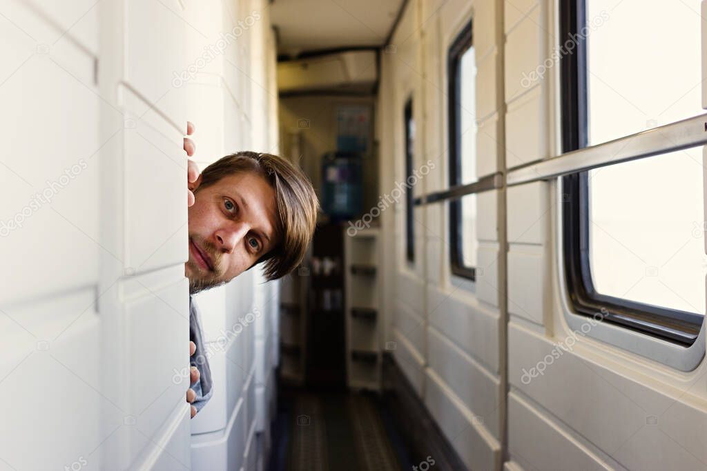 Portrait of cheerful beard man on the train. looking at camera. Curious fellow traveler from a nearby compartment on the train. Meeting on the travel