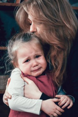 Anne ağlayan bir bebeğe sarılıyor. Aile bakımı kavramı