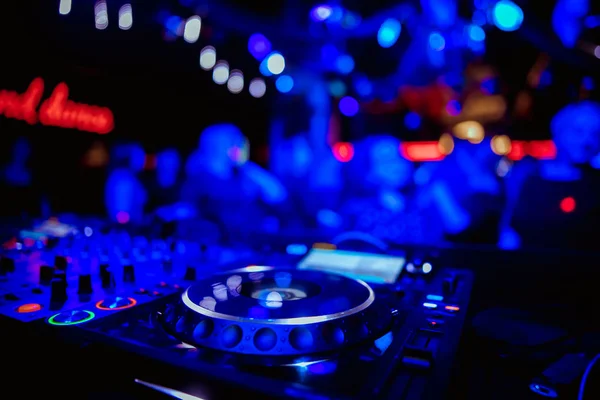 DJ plays live set and mixing music on turntable console at stage in the night club. Disc Jokey Hands on a sound mixer station at club party. DJ mixer controller panel for playing music and partying.