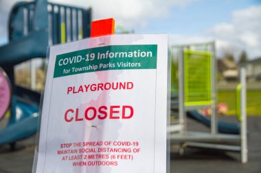 Küçük bir çocuk parkının önünde COVID-19 için kapalı bir oyun alanı tabelası.