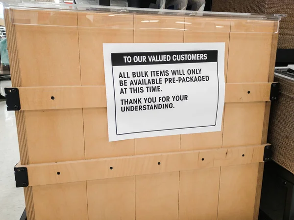 A bulk bin at the grocery store displays a sign stating that bulk items are only available pre-packaged, due to the Covid-19 pandemic.