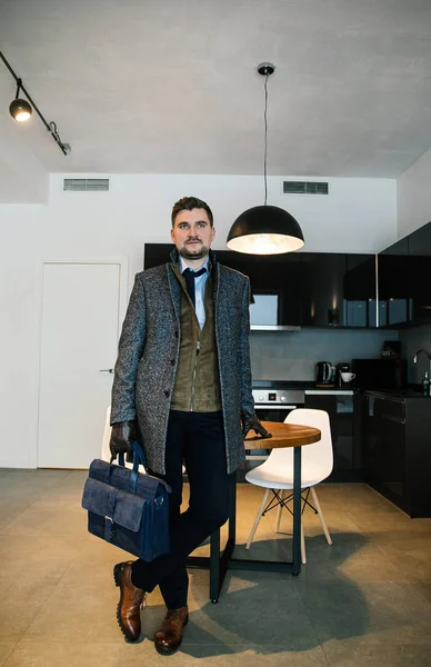 fashionably dressed businessman with a beard - stylish suit, brown shoes, tie, gloves, a man posing in an expensive apartment