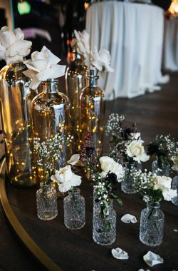 şık ve pahalı bir düğün dekoru, cam vazolarda çiçekler, altın, ışıklar, mumlar. 