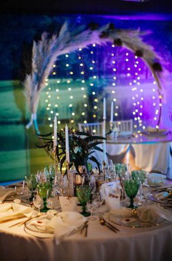 şık ve pahalı düğün dekoru, altın, mum, ışık, çiçek, şık bardaklar ve tabaklar kullanarak masa düzenleme