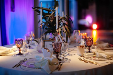 şık ve pahalı düğün dekoru, altın, mum, ışık, çiçek, şık bardaklar ve tabaklar kullanarak masa düzenleme