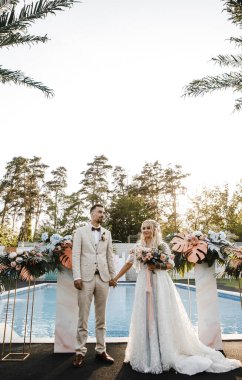 Sevgili gelin ve damat gün batımında bir düğün töreninde nazikçe birbirlerine bakıyorlar.