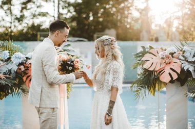 Sevgili gelin ve damat gün batımında bir düğün töreninde nazikçe birbirlerine bakıyorlar.