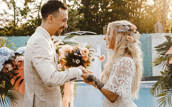 Sevgili gelin ve damat gün batımında bir düğün töreninde nazikçe birbirlerine bakıyorlar.