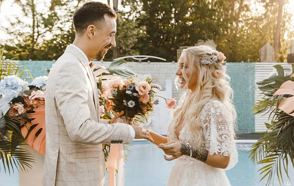 Sevgili gelin ve damat gün batımında bir düğün töreninde nazikçe birbirlerine bakıyorlar.