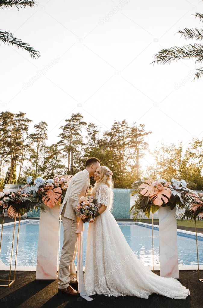 loving bride and groom at a wedding ceremony at sunset gently looking at each other