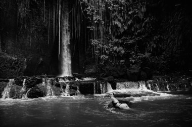 Bali adasında Endonezya 'ya seyahat ederken mayo giymiş sarışın bir blog yazarı vahşi bir şelalede cinsel olarak poz veriyor.