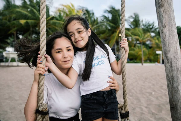 cute asian girls girlfriends and sisters ride on a swing and have fun on the beach near the ocean on the island of Bali in Indonesia