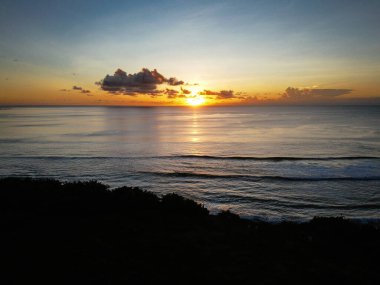 Endonezya 'daki cennet adası Bali' nin gün batımı kumsalı, okyanus ve orman, insansız hava aracından alınan fotoğraf.