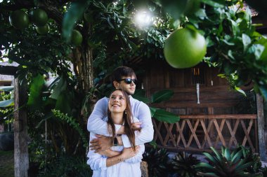 Birbirine aşık çiftler, Endonezya 'nın Bali adasında, meyve bahçesinin yakınında romantik bir yürüyüşte kucaklaşıp eğleniyorlar.