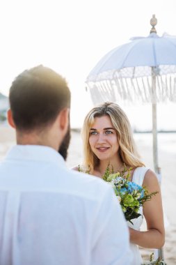 Birbirine aşık çiftler - gelin ve damat düğün günlerinde okyanus kenarında, Endonezya 'nın egzotik Asya adası Bali' de sarılıp öpüşürler. 