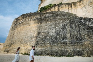Birbirine aşık çiftler - gelin ve damat düğün günlerinde okyanus kenarında, Endonezya 'nın egzotik Asya adası Bali' de sarılıp öpüşürler. 
