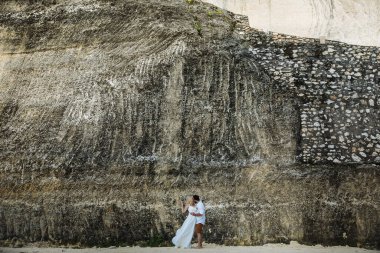 Birbirine aşık çiftler - gelin ve damat düğün günlerinde okyanus kenarında, Endonezya 'nın egzotik Asya adası Bali' de sarılıp öpüşürler. 