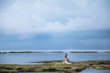 Birbirine aşık çiftler - gelin ve damat düğün günlerinde okyanus kenarında, Endonezya 'nın egzotik Asya adası Bali' de sarılıp öpüşürler. 