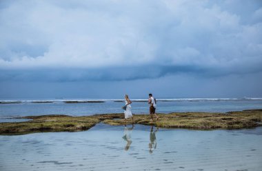 Birbirine aşık çiftler - gelin ve damat düğün günlerinde okyanus kenarında, Endonezya 'nın egzotik Asya adası Bali' de sarılıp öpüşürler. 