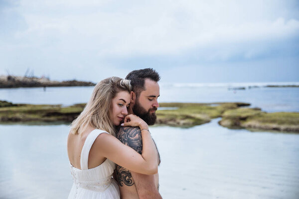 couple in love - bride and groom on their wedding day hug and kiss on the beach near the ocean on the exotic Asian island of Bali in Indonesia