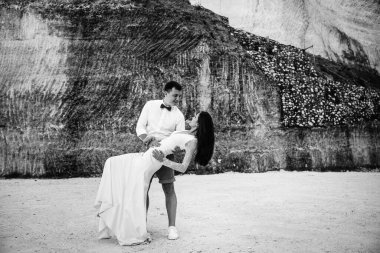 Birbirine aşık çiftler - gelin ve damat düğün gününde okyanusun kıyısında, Endonezya 'nın egzotik Asya adası Bali' de kucaklaşıp öpüşürler, inanılmaz manzara