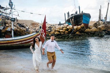 Birbirine aşık çiftler - gelin ve damat düğün günü sahilde kucaklaşıp öpüşürler Endonezya 'nın egzotik Asya adası Bali' de, inanılmaz manzara, parlak balıkçı teknesi