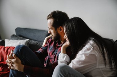 Beyaz gömlekli esmer ve kocası evde şık bir iç mekanda eğleniyor.