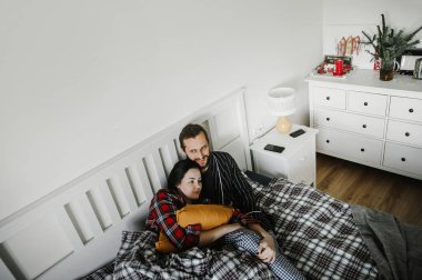 Mutlu bir aile evinde, şık bir iç mekanda yatakta sarılıyor.