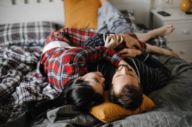 Mutlu bir aile evinde, şık bir iç mekanda yatakta sarılıyor.