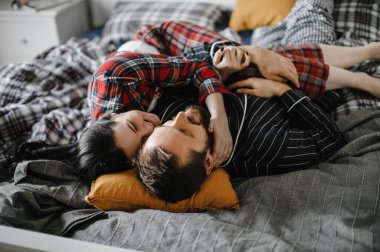 Mutlu bir aile evinde, şık bir iç mekanda yatakta sarılıyor.