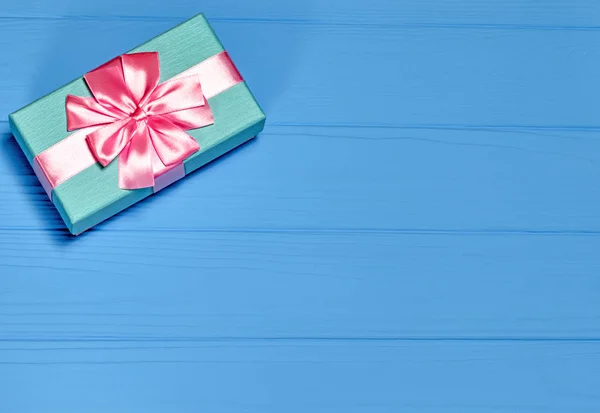 Modrý dárkový box utažený růžovou stuhou na modrém pozadí — Stock fotografie