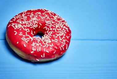 Mavi arka planda pembe jöleli donut.