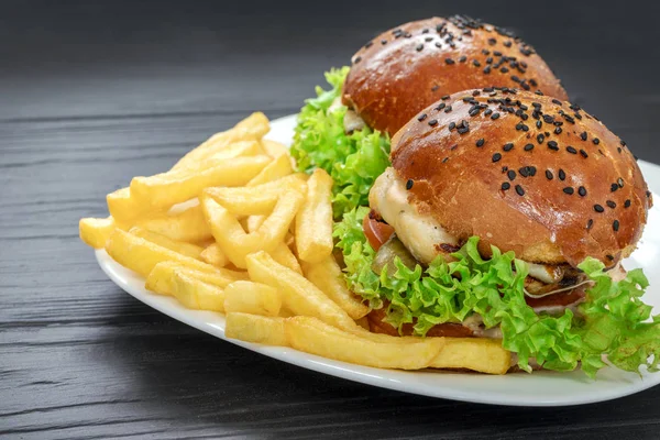Savoureux hamburgers appétissants sur un terrel blanc avec des frites sur un fond gris — Photo