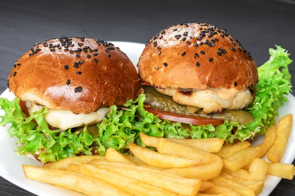 Smaczne, apetyczne hamburgery na białym terrelu z frytkami na szarym tle — Zdjęcie stockowe