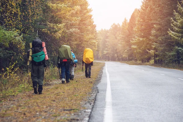 Group of friends walking with backpacks in sunset from back. — Stock Photo, Image