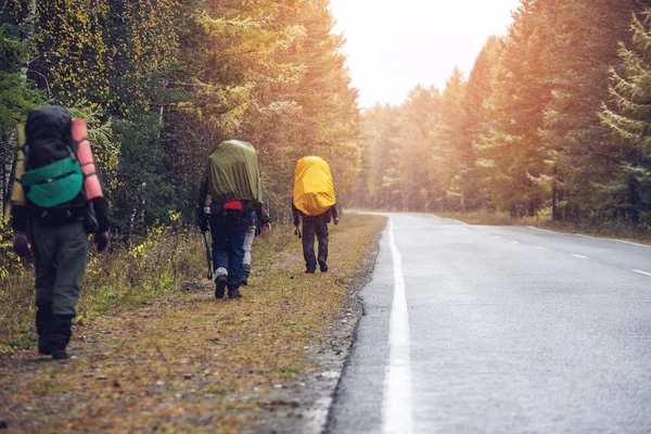 Group of friends walking with backpacks in sunset from back. — Stock Photo, Image