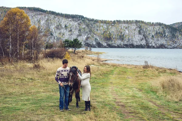 Incinta ragazza e suo marito in piedi accanto al cavallo — Foto Stock