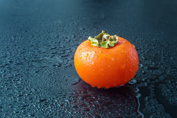 Ripe persimmons with water drops on black — Stock Photo, Image