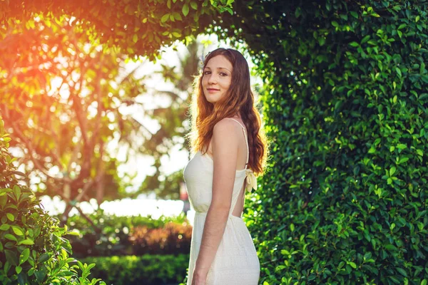 Mujer de pie sobre fondo de arbustos verdes forma como corazón — Foto de Stock