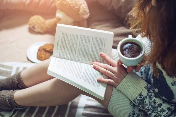 Ragazza lettura libro a letto con calze calde bere caffè — Foto Stock
