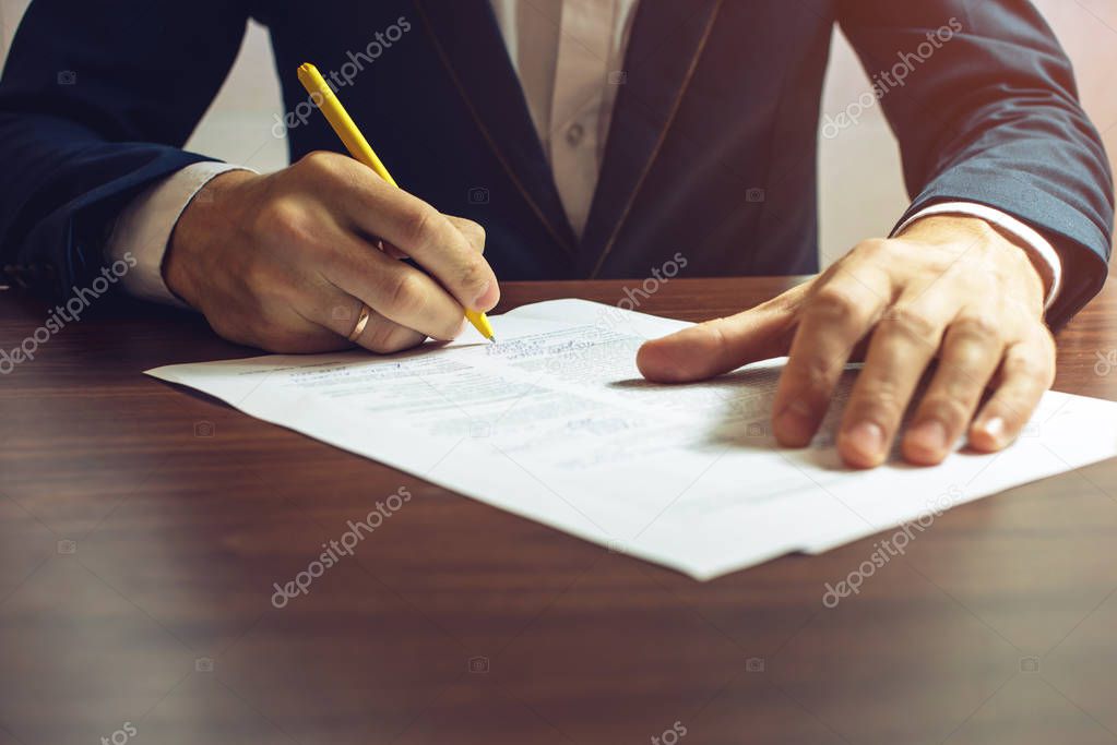 Man businessman signs documents with a pen