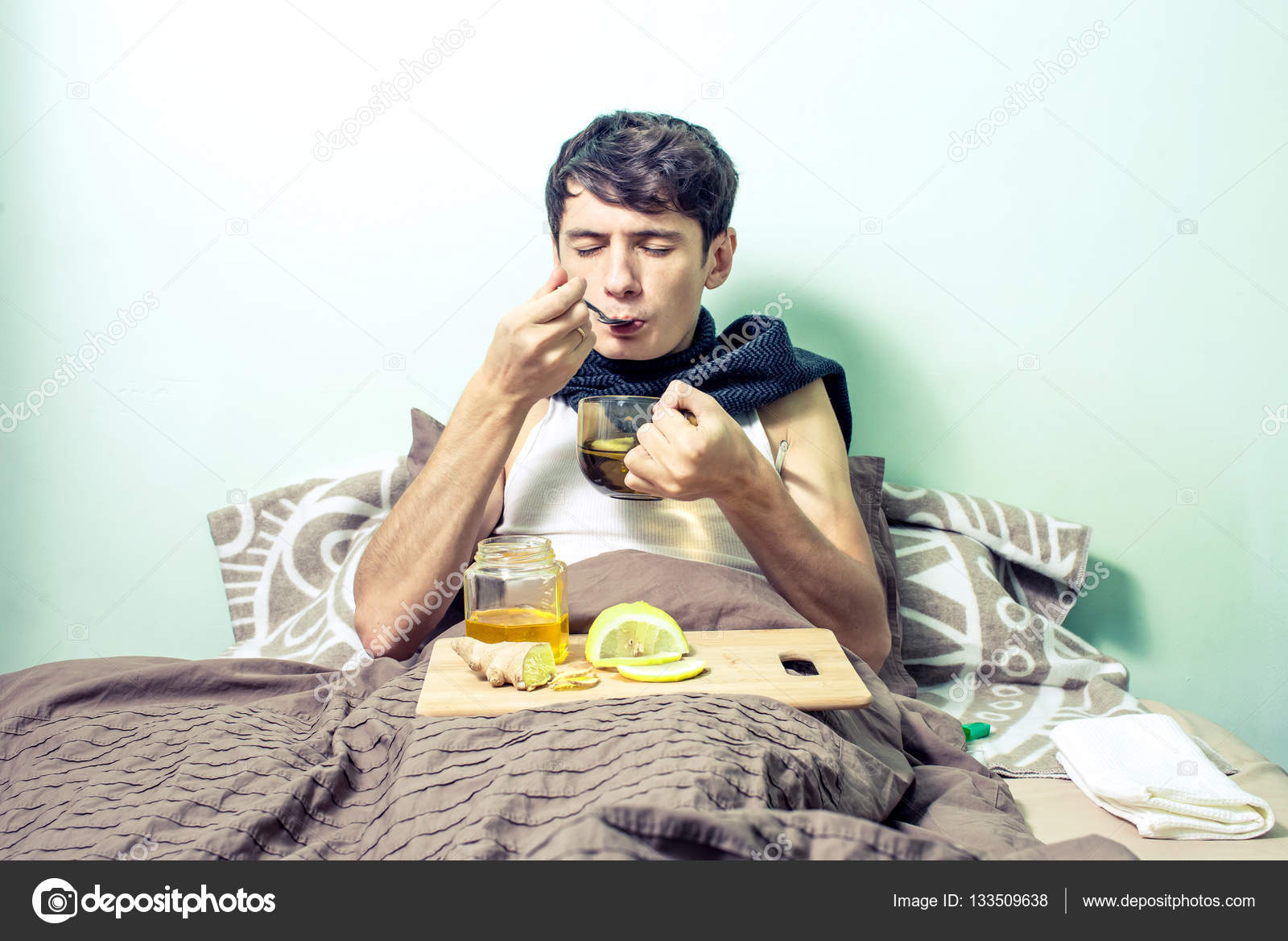 Junger Mann liegt krank mit Erkältung und Grippe im Bett ...