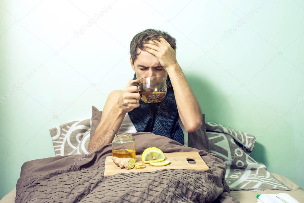 young man lies in bed sick with colds and flu