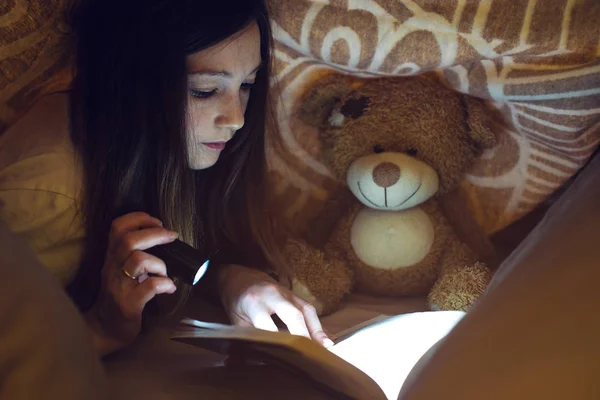 Молода дівчина читає чарівну книгу в темряві — стокове фото